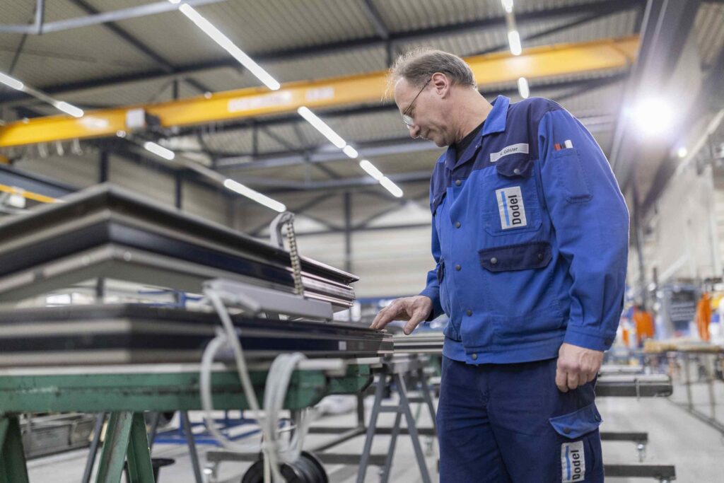 Ein Arbeiter ueberprueft Materialien in einer Produktionshalle.