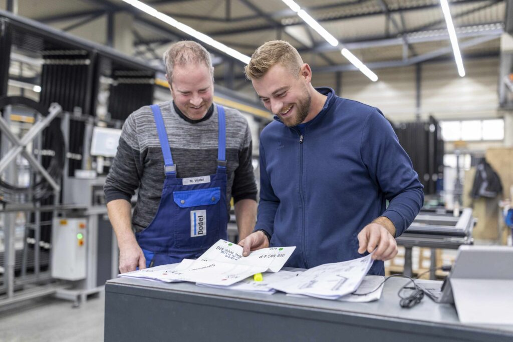 Zwei Mitarbeiter in einer Druckerei ueberpruefen Druckentwuerfe.