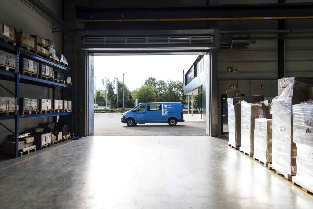 Blauer Transportwagen faehrt in eine Lagerhalle ein.