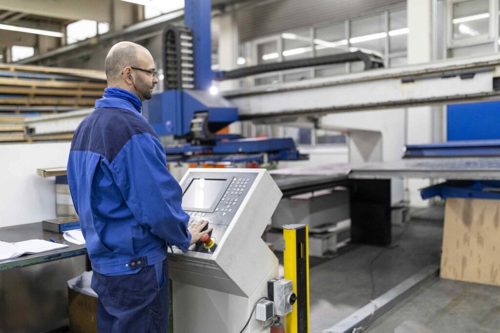 Ein Arbeiter bedient eine große Industrieanlage in einer Fabrikhalle.