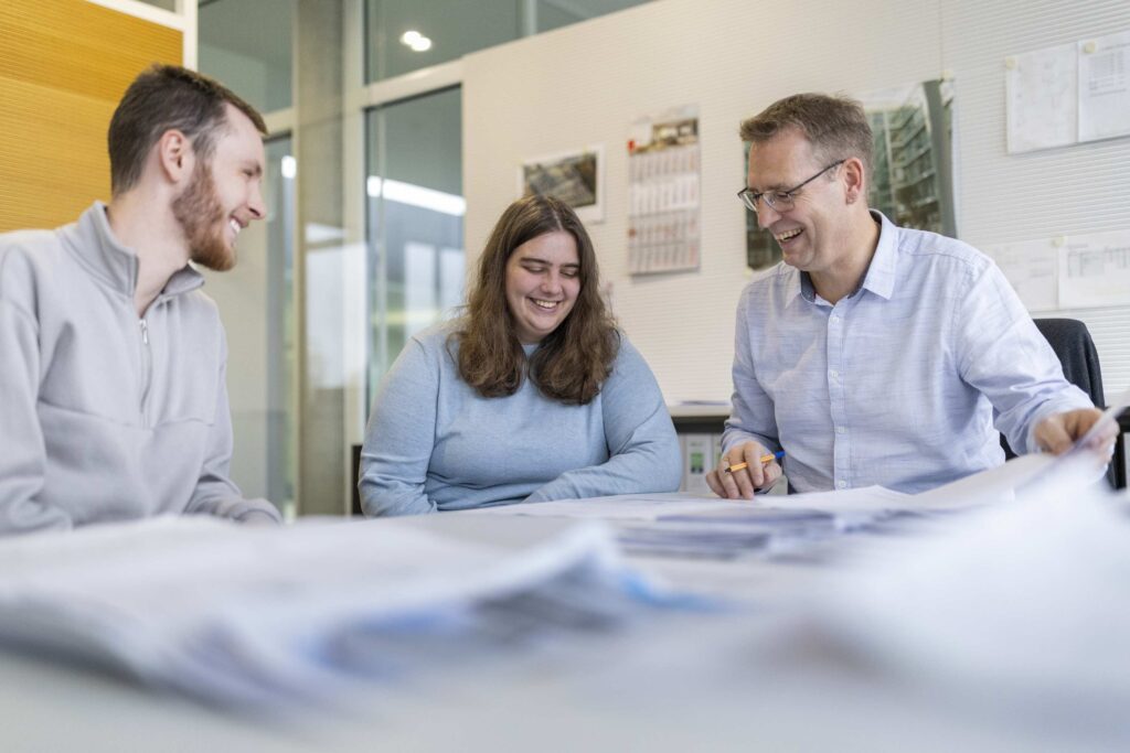 Menschen diskutieren Plaene in einem Bueroumfeld.