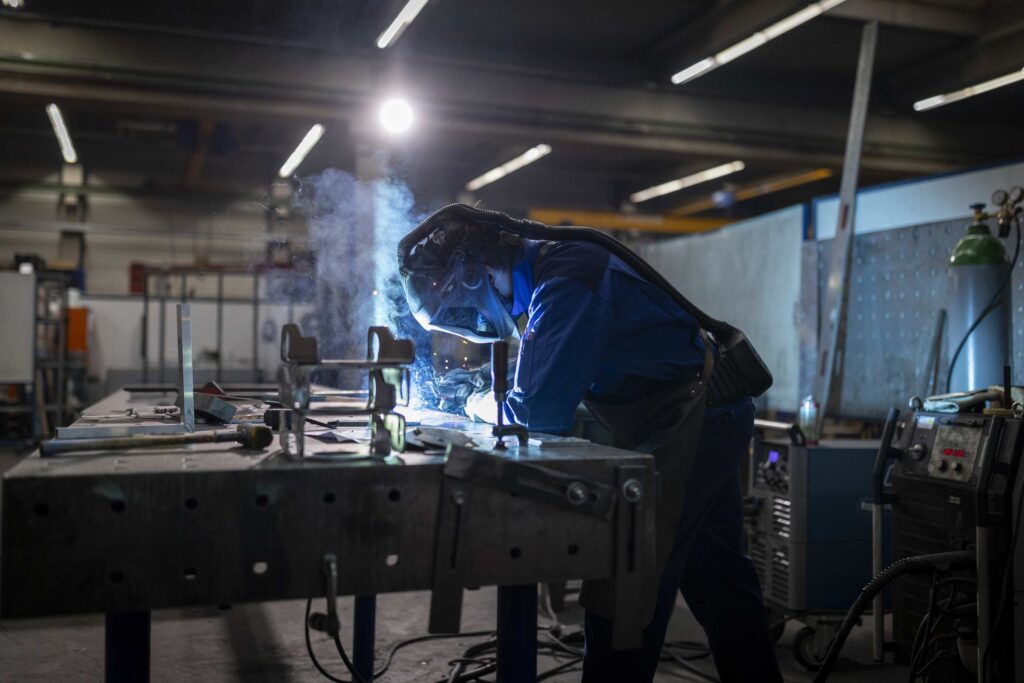 Person schweißt Metall in einer Werkstatt.