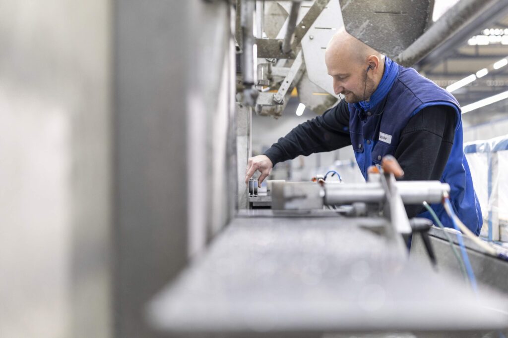 Ein Arbeiter bedient eine Maschine in einer Fabrikhalle.