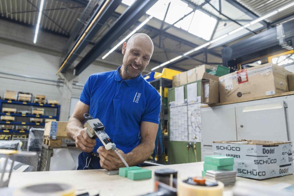 Mann in einer Werkstatt benutzt Werkzeuge und Materialien auf einem Tisch.