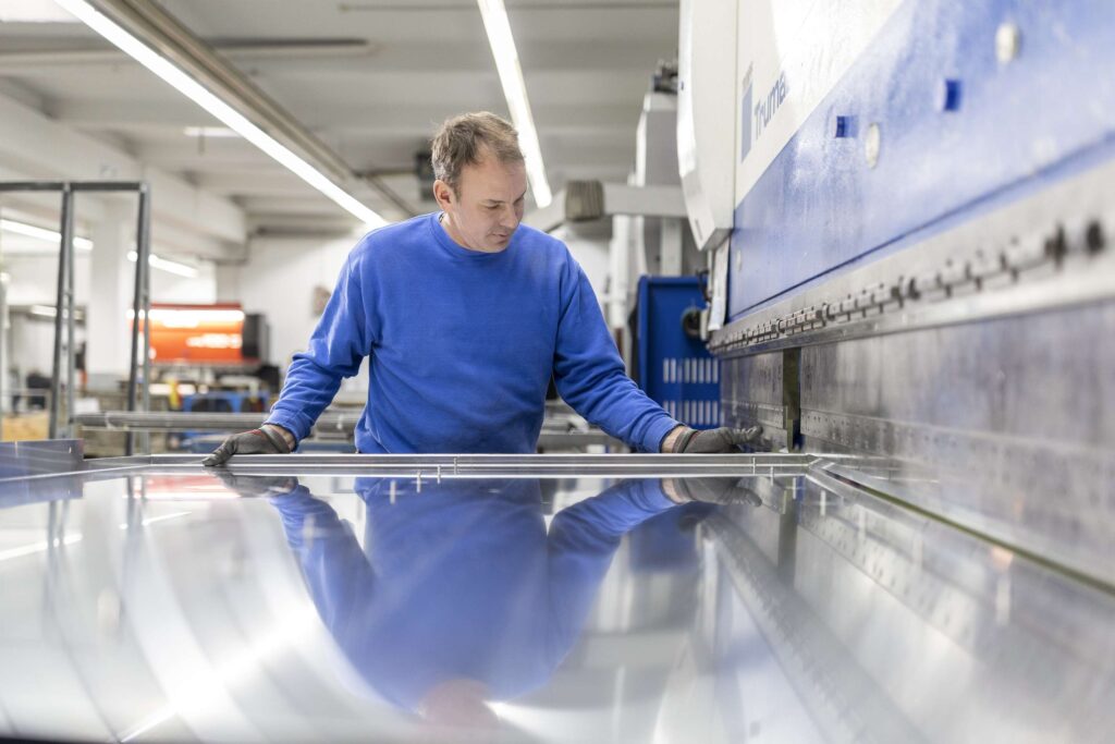 Mitarbeiter der Dodel Metallbau GmbH bearbeitet ein Blech in der Werkstatt.