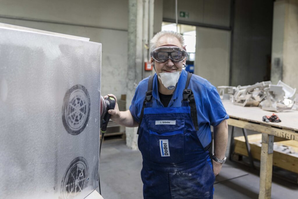 Ein Eisbildhauer traegt Schutzkleidung und arbeitet in einer Werkstatt.