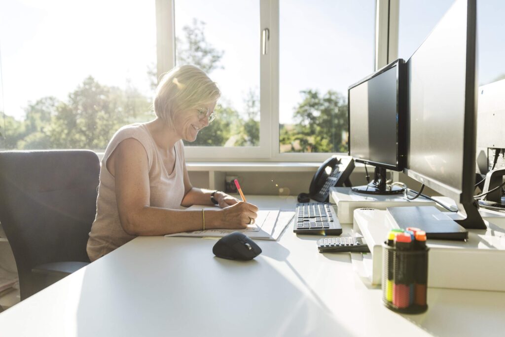 Frau arbeitet am Schreibtisch mit einem Computer.